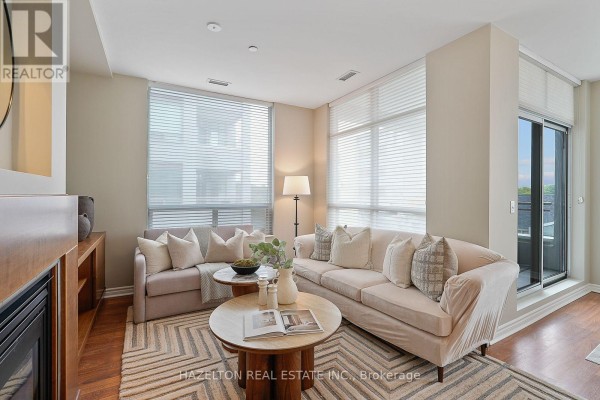 Living room with beige sofas, patterned rug, and floor-to-ceiling windows. - 501 - 980 Yonge Street, Toronto