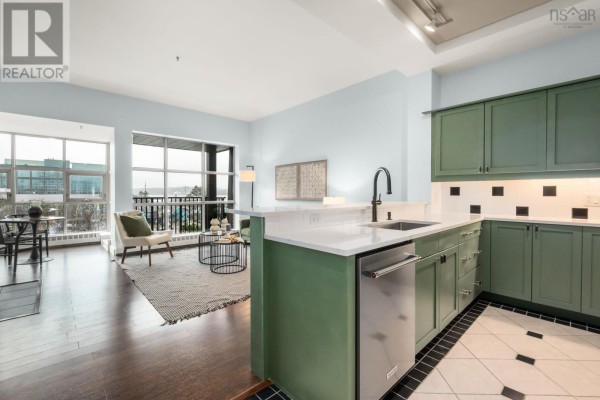 Open concept living area and kitchen with light blue walls, green cabinets, and large windows. - 501 1479 Lower Water Street, Halifax