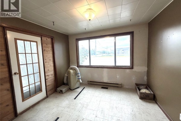Room with large window, wood-paneled wall, and portable air conditioner. - 501 Churchill Street, Hudson Bay