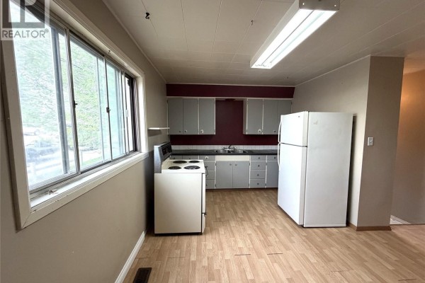 Kitchen with light wood floors, gray cabinets, white refrigerator, and stove. - 501 Churchill Street, Hudson Bay