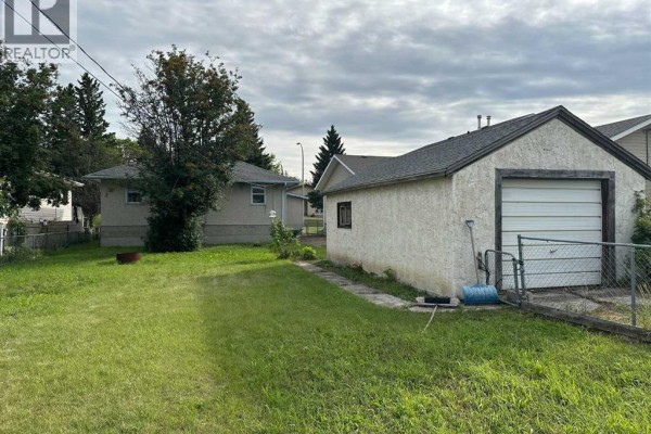Backyard view of the house with a detached garage and a fenced yard. - 5010 44 Avenue, Ponoka