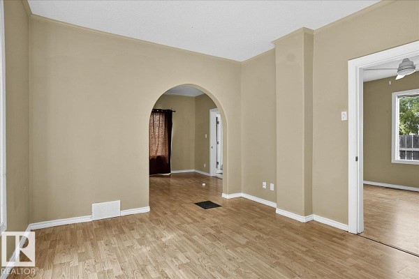 Living room with beige walls, hardwood floors, an arched doorway leading to another room. - 5010 52 Av Nw, Wetaskiwin