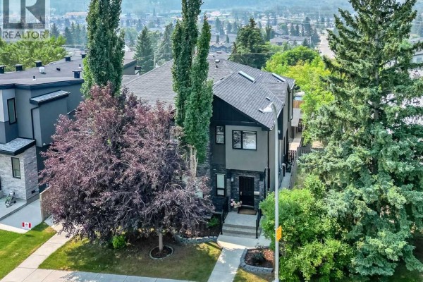 Aerial view of a duplex with dark grey and stone exterior, surrounded by trees. - 5013 23 Avenue Nw, Calgary