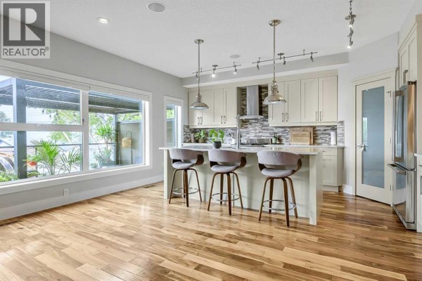Kitchen with island, light beige cabinets, and large window overlooking backyard. - 5013 23 Avenue Nw, Calgary