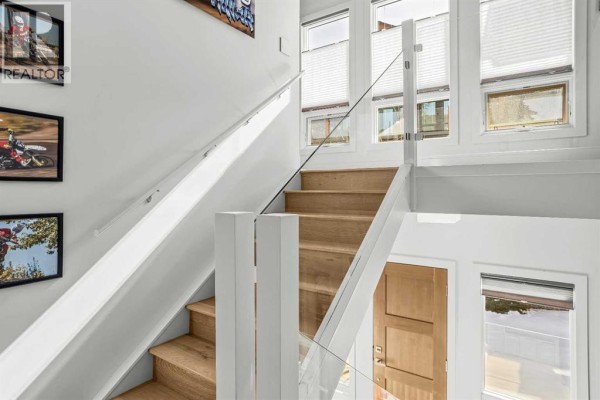 Interior staircase with wooden steps and glass railing, leading to upper level - 501h, 3000 Stewart Creek Drive, Canmore