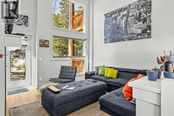 Living room with large windows, modern furniture, and colorful cushions, featuring a cozy atmosphere - 501h, 3000 Stewart Creek Drive, Canmore