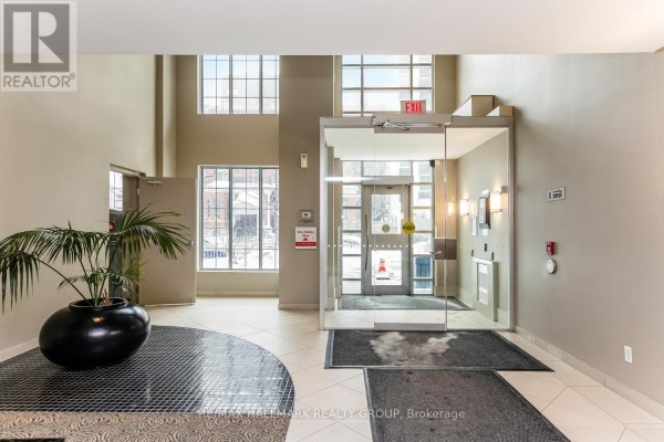 Building entrance lobby with glass doors, planters, and tiled floors. - 502 - 138 Somerset Street W, Ottawa