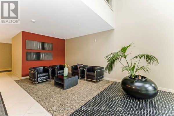 Apartment building lobby seating area with black leather chairs and a red accent wall. - 502 - 138 Somerset Street W, Ottawa
