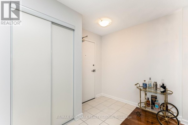 Hallway inside an apartment with a closet, front door, and a bar cart. - 502 - 138 Somerset Street W, Ottawa