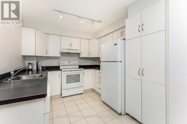 White kitchen with black countertops, white appliances, and tiled floors. - 502 - 138 Somerset Street W, Ottawa