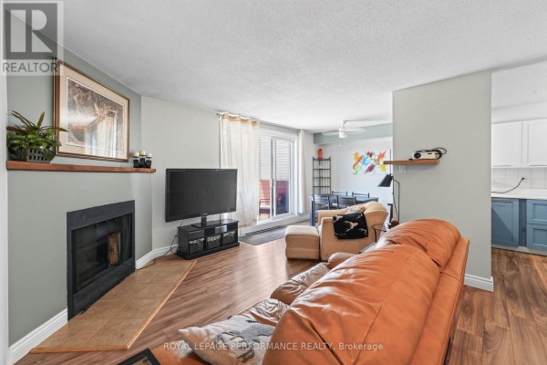 Living room with a fireplace, television, and view of the balcony. - 502 - 1589 St Bernard Street, Ottawa