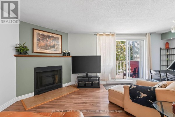 Living room with a fireplace, television, and balcony door. - 502 - 1589 St Bernard Street, Ottawa