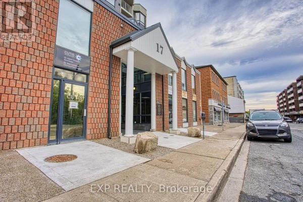 Exterior view of brick building entrance with white columns and signage. - 502 - 17 King Street E, Hamilton