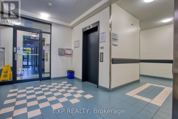 Elevator lobby with blue and white checkered floor and glass entrance doors. - 502 - 17 King Street E, Hamilton