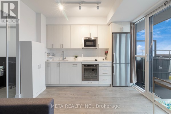 Modern apartment kitchen with white cabinets, stainless steel appliances, and light wood floors. - 502 - 2550 Simcoe Street N, Oshawa