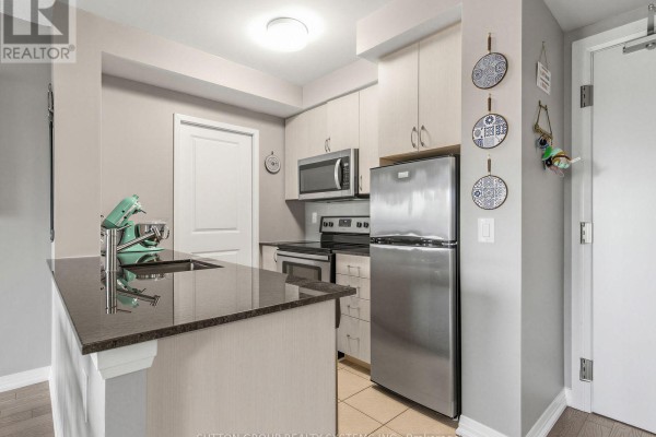 Close-up view of a kitchen island with a granite countertop, stainless steel appliances, and light wood cabinetry. - 502 - 741 Sheppard Avenue W, Toronto