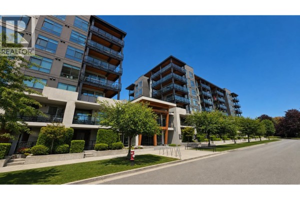 Exterior of a modern apartment building with balconies and trees. - 502 128 E 8th Street, North Vancouver