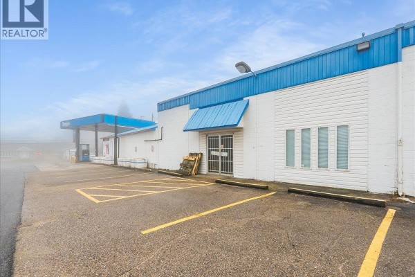 Exterior of the liquor store with parking lot, loading dock, and a glass-paneled entrance. - 502 12th Avenue, Genelle