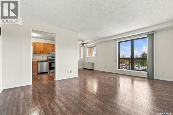 Living room with dark wood floor and large window overlooking the city. - 502 430 5th Avenue N, Saskatoon