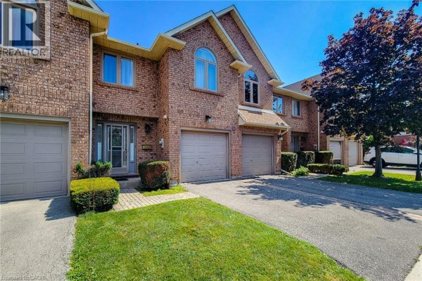 Front view of brick townhouses with manicured lawns and paved driveways. - 502 Barton Street Unit# 50, Stoney Creek