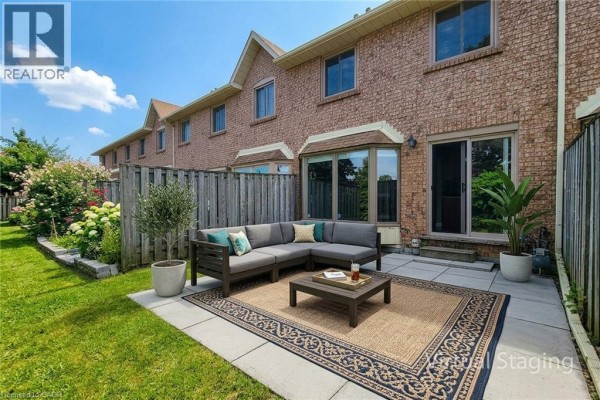 Backyard patio with a barbecue and lawn furniture, enclosed by a wooden fence. - 502 Barton Street Unit# 50, Stoney Creek