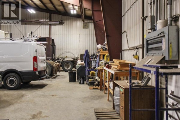 Interior workshop detail showing a white van, semi-truck chassis, and workbenches with tools. - 5022 50 Avenue, Lougheed