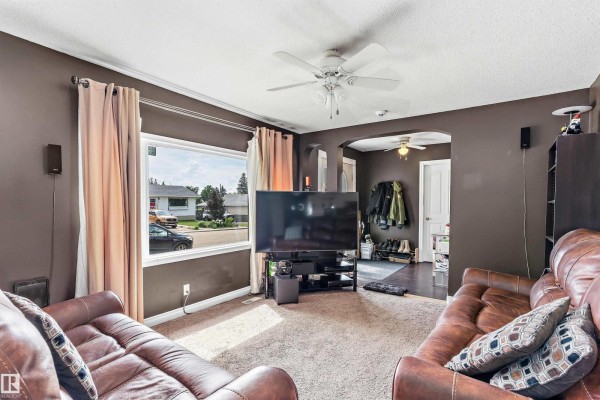 Living room with brown walls, tan carpet, and leather furniture. - 5024 55 Av, Tofield
