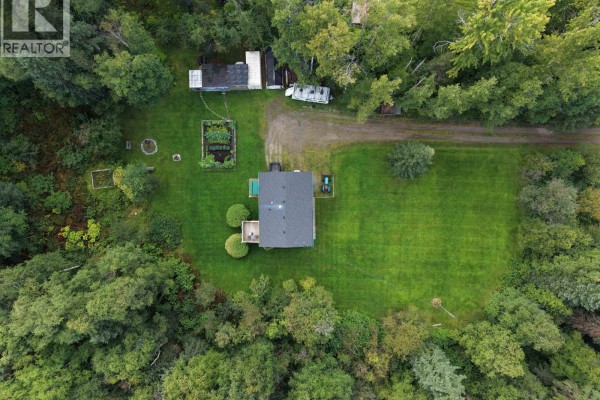 Overhead drone view of the residential property featuring a house, garden, and wooded surroundings. - 5027 Sooke Road, Prince George