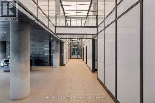Modern building hallway with concrete columns and illuminated panel walls. - 503 - 28 Eastern Avenue, Toronto