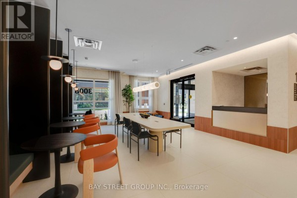 Communal lounge with a long table, chairs, seating, and large windows. - 503 - 3008 William Cutmore Boulevard, Oakville