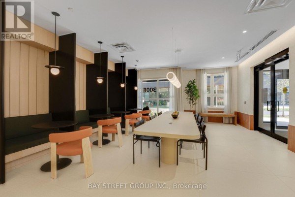 Communal lounge with a long table, seating booths, chairs, and large windows. - 503 - 3008 William Cutmore Boulevard, Oakville