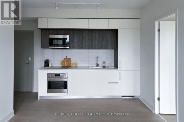 Modern kitchen with white and dark wood cabinetry, stainless steel appliances, and tile backsplash. - 503 - 322 Dupont Street, Toronto