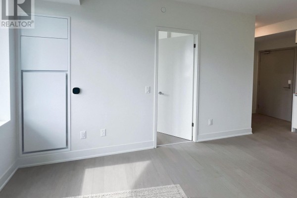 Empty room with white walls, light wood floors, and a built-in white cabinet. - 503 - 322 Dupont Street, Toronto