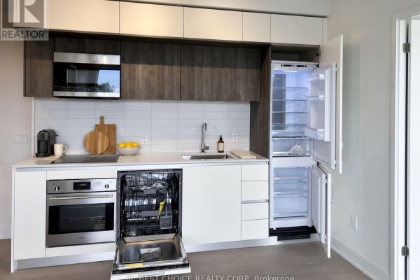 Kitchen with open dishwasher, stainless steel oven, white and dark cabinetry, and open refrigerator. - 503 - 322 Dupont Street, Toronto