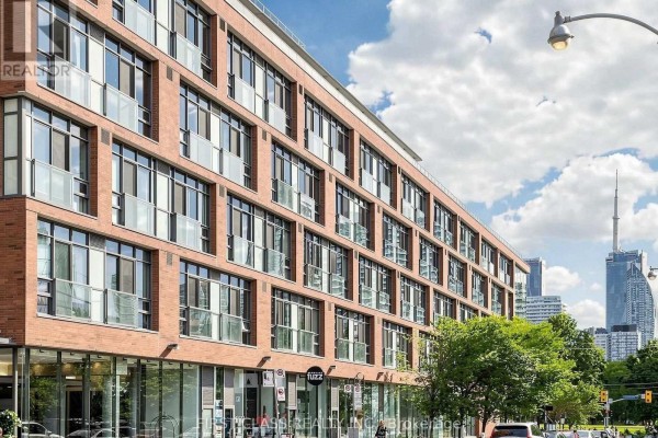 Brick condo building with many windows and a cloudy blue sky. - 503 - 33 Mill Street, Toronto
