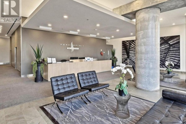 Lobby seating area with black leather chairs, artwork, and concierge desk. - 503 - 33 Mill Street, Toronto