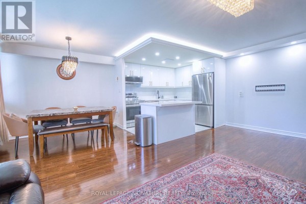 Dining area with a marble-topped table and bench seating next to a sleek white kitchen. - 503 - 3590 Kaneff Crescent, Mississauga