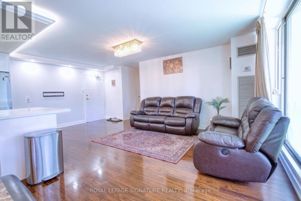 Living area with leather furniture, a red rug, and large windows looking out onto the city. - 503 - 3590 Kaneff Crescent, Mississauga