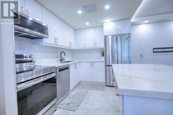 Modern white kitchen with stainless steel appliances, a dishwasher, and a marble-topped island. - 503 - 3590 Kaneff Crescent, Mississauga