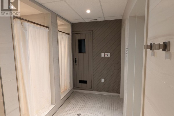 Changing room with two shower stalls and a wooden sauna door. - 503 - 600 Talbot Street, London East
