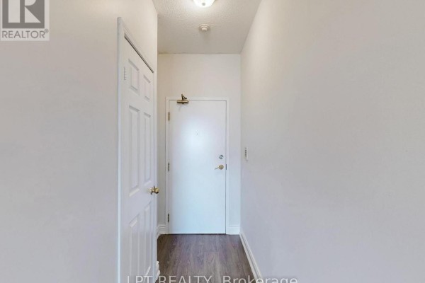 Interior view of a small, white hallway with a closed door and a single light fixture. - 503 - 8 Hillcrest Avenue, Toronto