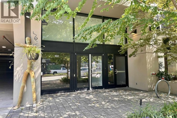 Entrance to the apartment building with glass doors and decorative plants. - 503 160 W 3rd Street, North Vancouver