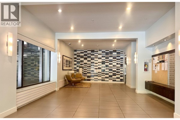 The building's lobby features tile floors, modern seating, and a striking black and white wall. - 503 160 W 3rd Street, North Vancouver