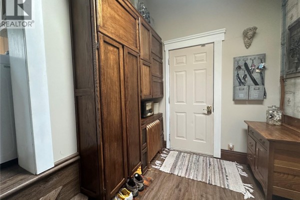 Hallway with a large wooden cabinet, a radiator, and a beige door. - 503 Bison Avenue, Weyburn