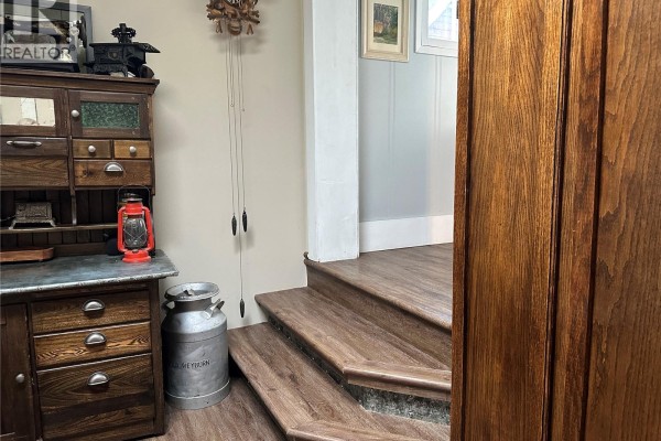 Wooden stairs leading up beside a vintage cabinet with a red lantern. - 503 Bison Avenue, Weyburn