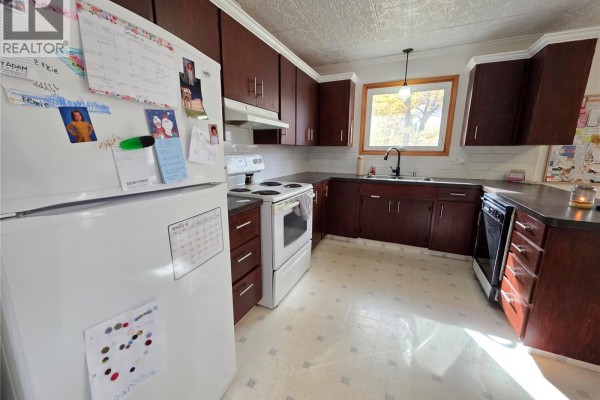 Kitchen with dark brown cabinets, white appliances, and a textured ceiling. - 503 Thompson Street, Herbert