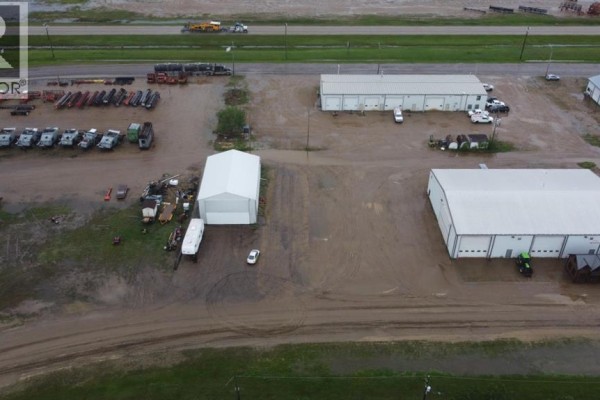 Aerial view of commercial buildings, some flooded, with equipment and vehicles on the property. - 5030 50 Avenue, Lougheed