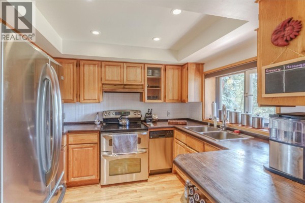Kitchen with light wood cabinets, stainless steel appliances, and a double sink. - 5031 Gloinnzun Drive, 108 Mile Ranch