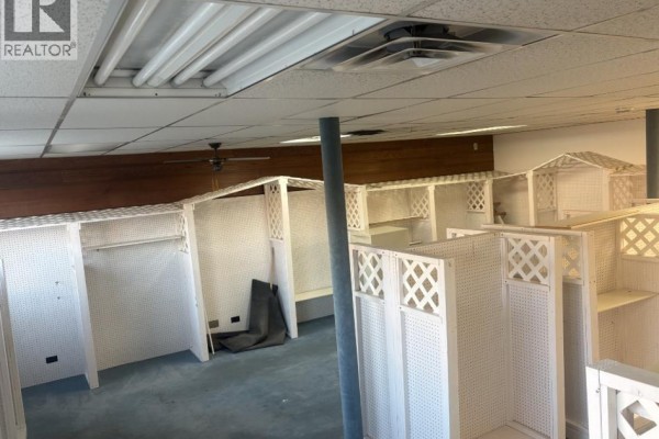 Interior view of a commercial space with white pegboard walls, shelving units, and blue carpet. - 5033 50ave, Ponoka