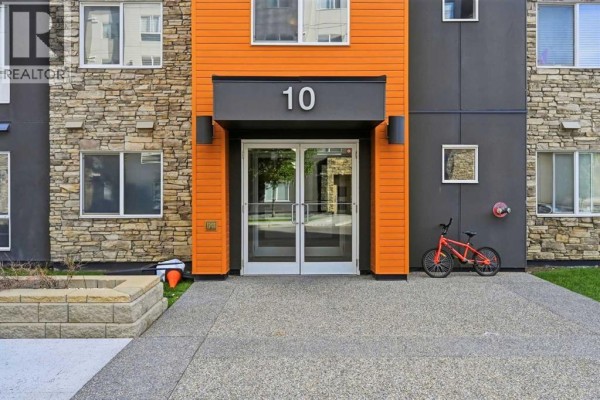 Close-up of the building entrance with double glass doors, orange siding, and number 10. - 504, 10 Kincora Glen Park Nw, Calgary